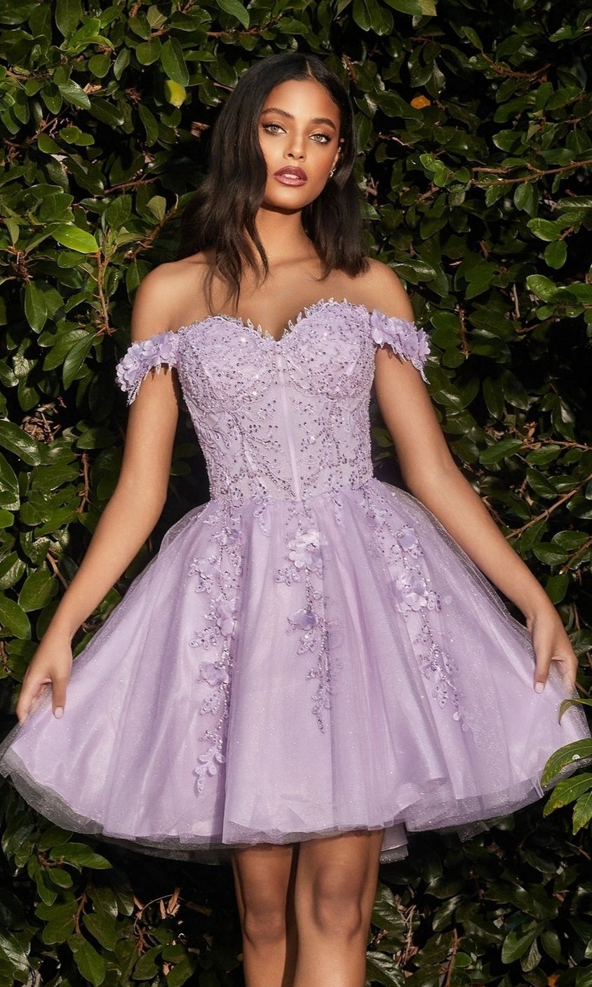 A woman wearing the Off-Shoulder Short Floral Homecoming Dress CD0194 stands before lush green foliage.